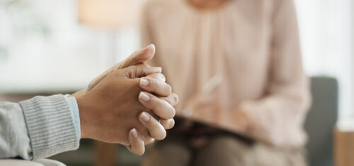 manos juntas de una mujer en la consulta con su psicológa