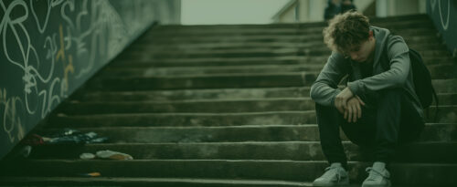 Escaleras con un joven deprimido mirando al suelo.